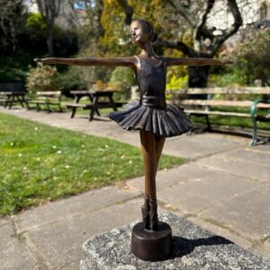 Bronze pirouette ballerina sculpture displayed in elegant park garden setting with soft natural surroundings