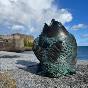 Bronze koi carp water feature sculpture with verdigris patina beside the sea in Guernsey