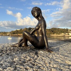 Seated Nude Woman Bronze Sculpture – Elegant Feminine Garden Figure FIWO57 side view overlooking a peaceful Guernsey bay