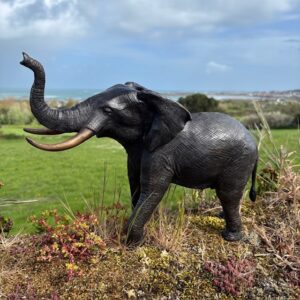Bronze elephant garden sculpture with raised trunk overlooking coastal landscapes