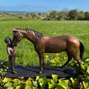 Solid Bronze Girl Holding Horse Sculpture HO 5 full side profile showing horse and young rider interaction in coastal garden setting