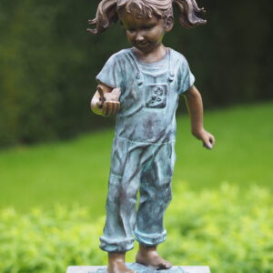 Bronze young girl holding bird sculpture with verdigris dungarees and playful figurative detail