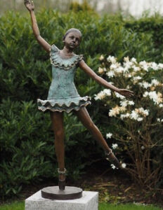 Bronze girl ballet dancer sculpture performing an elegant pose with verdigris costume inspired by classical dance
