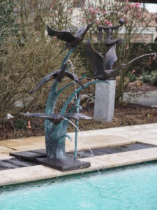 Flock of wild ducks flying bronze fountain sculpture with four water jets and dramatic wave base