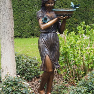 Bronze fountain sculpture of woman holding bowl with birds in classical garden setting
