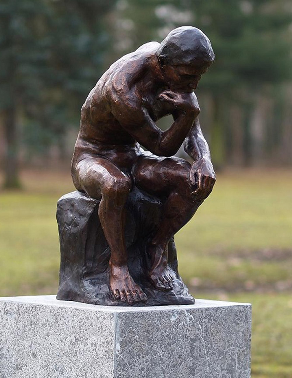 Bronze thinker sculpture inspired by Rodin showing a seated male nude in deep contemplation