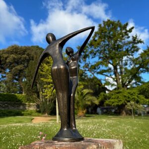 Abstract bronze couple sculpture displayed in a sunny garden setting