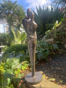 Forever loving couple bronze sculpture in garden setting with palm backdrop