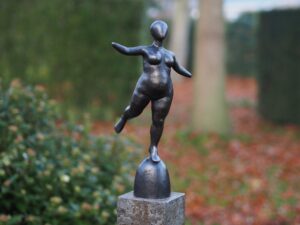 Modern bronze balancing female figure sculpture standing on rounded base
