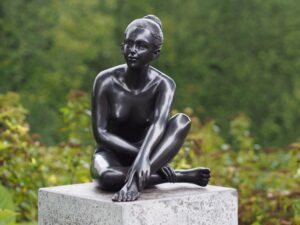 Contemporary bronze female figure sculpture with elegant seated pose and dark bronze patina