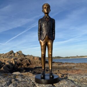 Handsome Young Man Suited Boy Bronze Sculpture BO 42 standing on coastal granite rocks with sea views and dramatic blue skies.