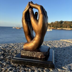 Rodin Clasping Hands Bronze Sculpture – Timeless Love & Unity CL 4 front view beside the sea in warm evening light.
