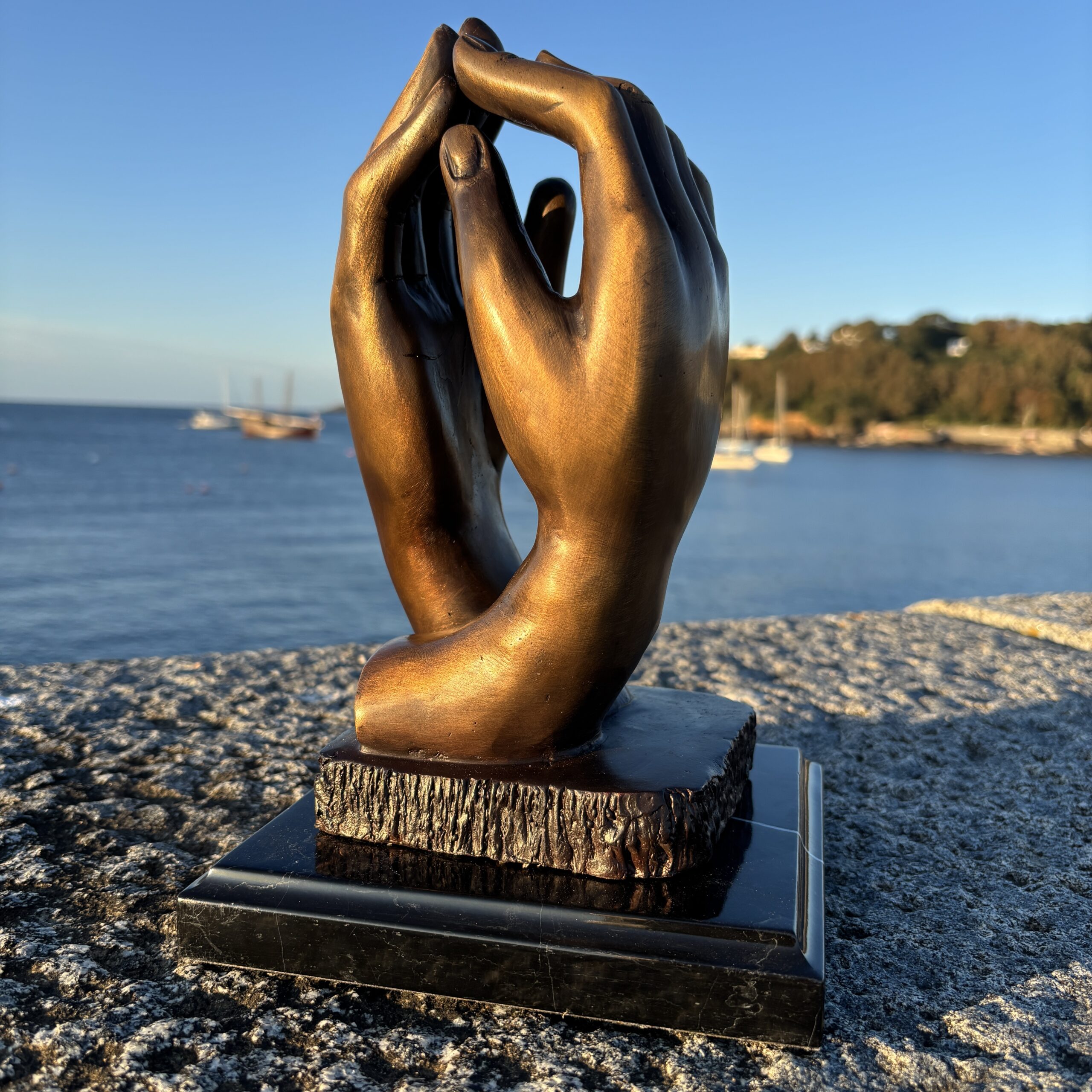 Rodin Clasping Hands Bronze Sculpture – Timeless Love & Unity CL 4 front view beside the sea in warm evening light.