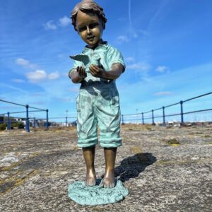 Bronze boy sculpture holding bird full view outdoor