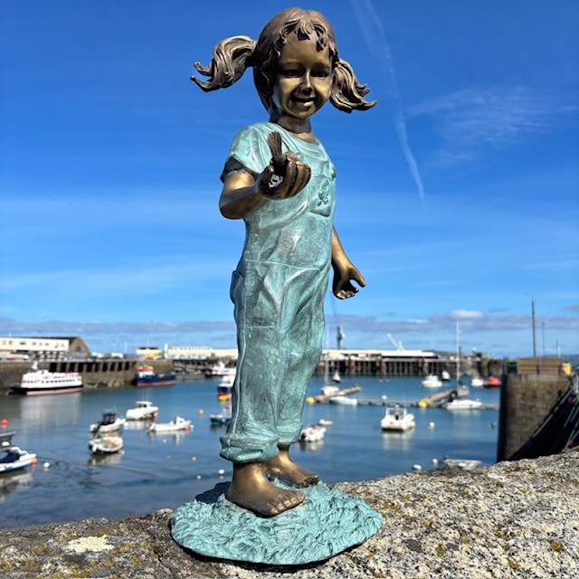 Bronze girl sculpture holding bird in hand harbour view