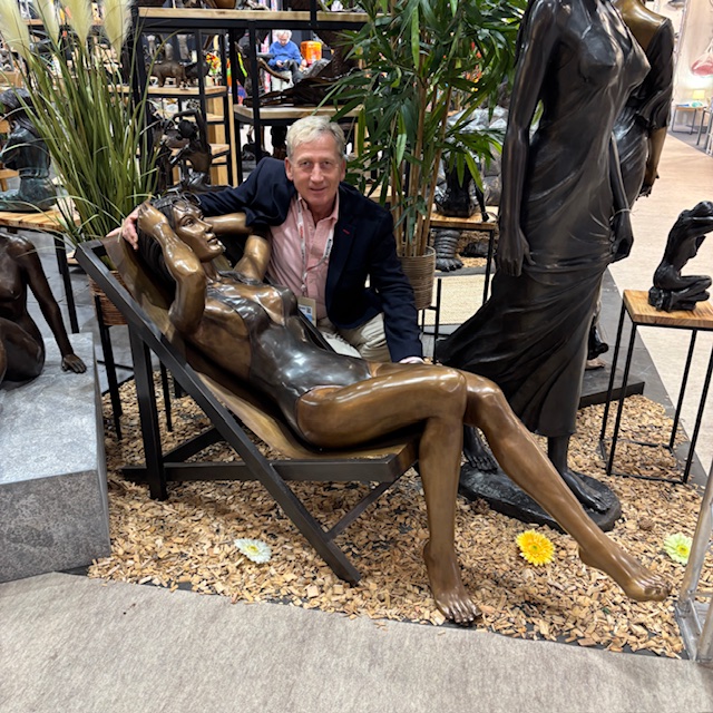 Large bronze sunbathing lady sculpture reclining on a deckchair in a relaxed garden setting