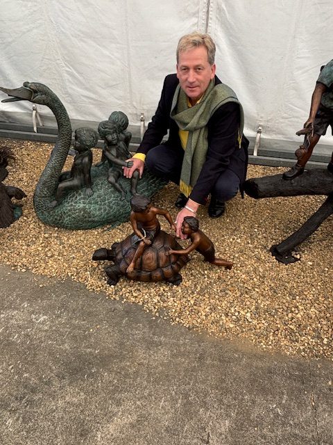 Bronze sculpture of boys playing with turtle fountain in garden setting