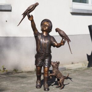 Bronze boy sculpture with parrots balancing on hands and playful dog