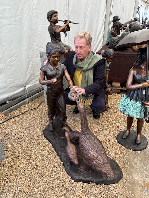 Bronze sculpture of young girl feeding geese and goslings in garden