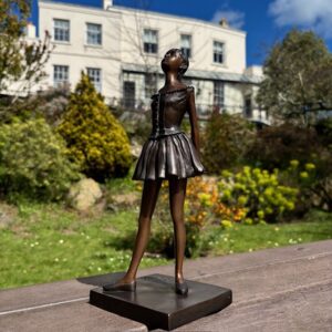 Bronze ballet dancer sculpture inspired by Degas standing outdoors in garden setting