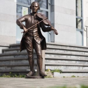 Bronze Mozart playing violin sculpture 170cm tall with detailed period costume in interior hall setting