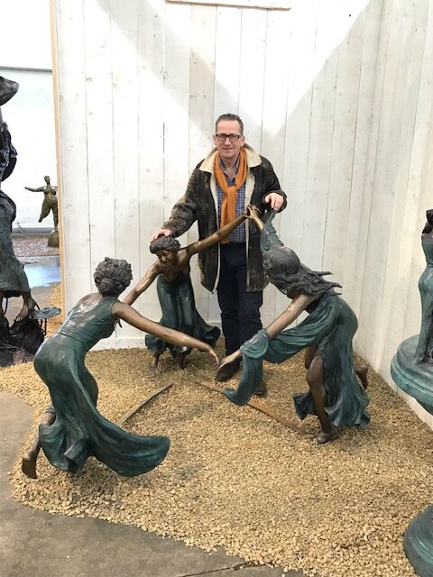 Large bronze sculpture of three women dancing in a circular formation