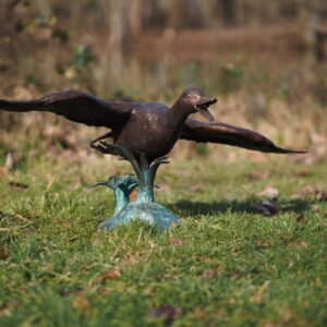 Bronze Flying Duck Water Feature Sculpture BI 105 low gliding pose on lawn with wings fully extended and natural outdoor setting