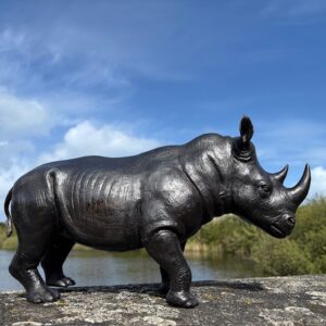 Bronze wildlife sculpture rhino in outdoor landscape setting in Guernsey