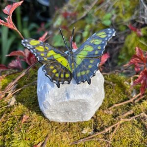 Green bronze malachite butterfly sculpture on quartz stone with subtle green wings displayed in a garden setting