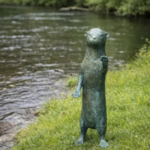 Curious Otter Bronze Garden Sculpture Fountain Water Feature WI 117 standing naturally beside a river in a waterside garden setting.